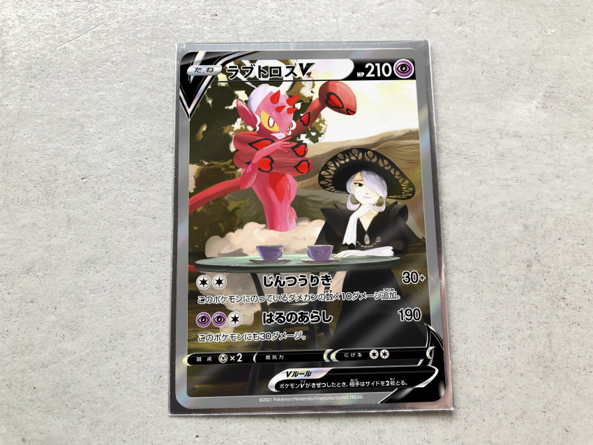 black_dress black_eyes black_headwear card card_(medium) character_name character_print closed_mouth cogita_(pokemon) commentary_request cup dress enamorus enamorus_(incarnate) female gloves grey_hair hair_over_one_eye hand_up hat head_rest highres looking_at_viewer official_style pokemon pokemon_legends:_arceus pokemon_tcg pokeyugami saucer short_hair smile table teacup white_gloves