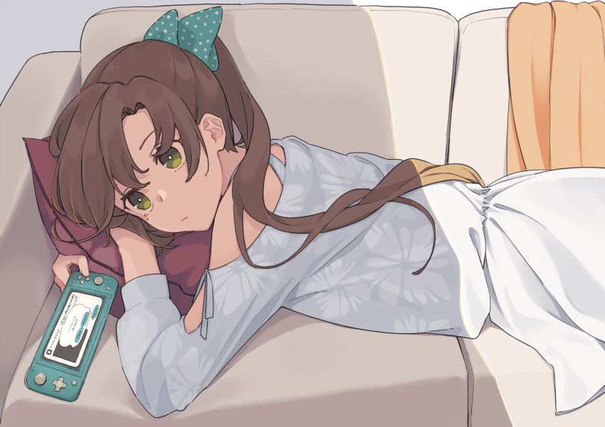 akigumo_(kancolle) brown_hair casual commentary_request couch cowboy_shot dress female green_eyes hair_ribbon handheld_game_console ichiroku_(sakumogu-029) kantai_collection long_hair lying nintendo_switch nintendo_switch_lite off_shoulder on_stomach polka_dot polka_dot_ribbon ponytail ribbon solo white_dress