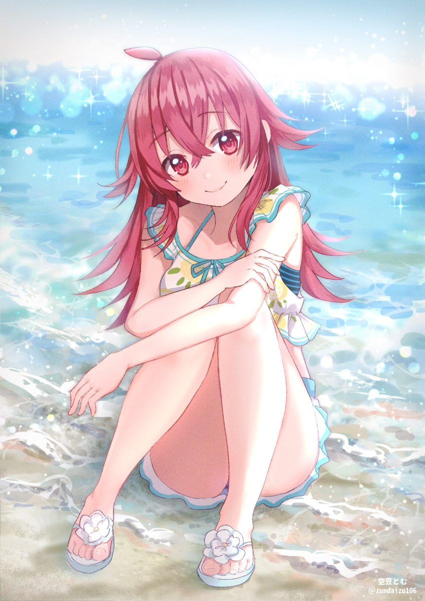 ahoge artist_name beach bikini bikini_skirt closed_mouth commentary day female frilled_bikini frills hand_on_own_arm head_tilt highres hugging_own_legs idolmaster idolmaster_shiny_colors komiya_kaho legs long_hair looking_at_viewer ocean outdoors red_eyes red_hair sandals sitting smile solo soramame_tomu sparkle swimsuit twitter_username waves white_bikini white_footwear