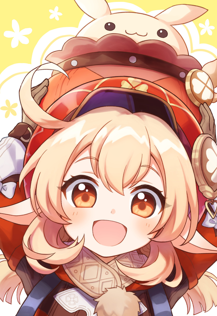 :3 :d arms_up blonde_hair brown_eyes brown_gloves eyelashes female genshin_impact gloves hair_between_eyes hat highres holding klee_(genshin_impact) light_blush long_sleeves looking_at_viewer low_twintails maruyama_en open_mouth pointy_ears red_hat side_ahoge smile solo twintails upper_body yellow_background