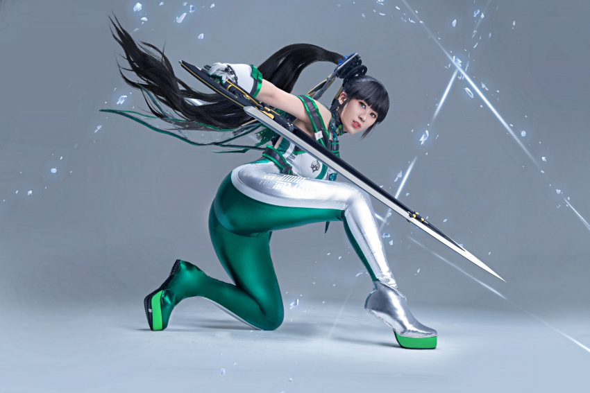 ass black_eyes black_hair bodysuit cosplay_photo english_commentary eve_(stellar_blade) female floating from_behind gloves green_bodysuit green_footwear grey_background grey_bodysuit grey_footwear highres holding holding_sword holding_weapon larissa_rochefort long_hair looking_at_viewer on_one_knee parted_lips photo_(medium) planet_diving_suit_(7th)_(stellar_blade) ponytail shadow sleeveless sleeveless_bodysuit solo stellar_blade sword two-tone_bodysuit very_long_hair weapon white_gloves