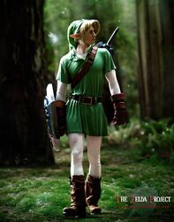  1boy belt blonde_hair boot cosplay forest full_body link male photo pointy_ears shield sword the_legend_of_zelda tunic wings 