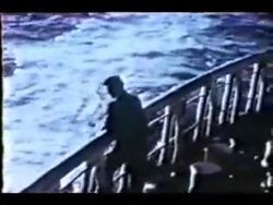  4:3 boat clothing coast_guard cutter day hair human low_res male mammal outside post_ww2 rail standing stern swell vehicle water watercraft 