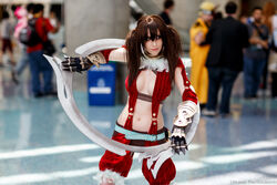  breasts brown_hair cleavage cosplay eyeshadow feathers female long_hair navel photo solo soul_calibur soulcalibur_iv standing tira_(soulcalibur) tira_(soulcalibur)_(cosplay) twintails 