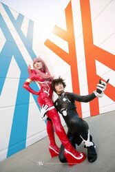  1boy bangs black_bodysuit black_hair blue_eyes bodysuit cosplay couple darling_in_the_franxx female gloves green_eyes hair_ornament hairband hiro_(darling_in_the_franxx) hiro_(darling_in_the_franxx)_(cosplay) horns long_hair oni_horns pilot_suit pink_hair red_bodysuit red_horns straight white_gloves white_hairband zero_two_(darling_in_the_franxx) zero_two_(darling_in_the_franxx)_(cosplay) 