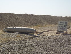 4:3 absurd_res beam_(structure) branch camo challenge defeatdown desert dirt english_text fuel_tank grandfathered_content grass hi_res improvised_explosive_device iraq iraq_war not_furry outside photo_background photography_(artwork) plant public real rock sandbag sign sky text what wood zero_pictured